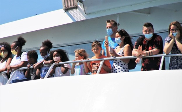 Tourists at rail of cruise ship with masks on